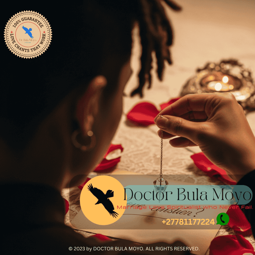 Person holding a pendulum over a written love question with rose petals nearby.